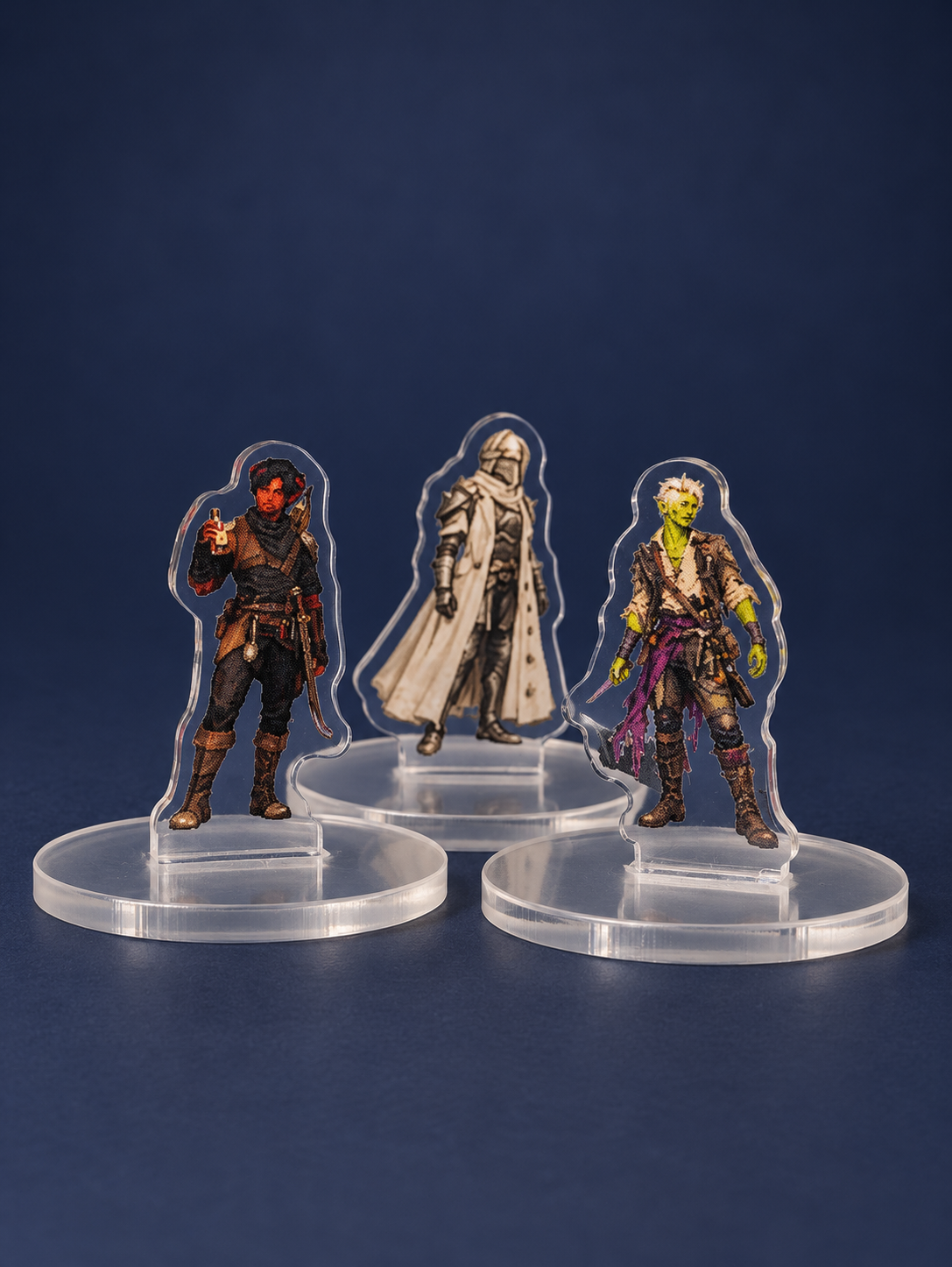 Retouched photograph of three fantasy test standees on clear bases against a navy background.